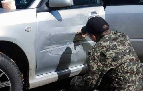 찌그러진 자동차 문짝에 그림을 그린 남자